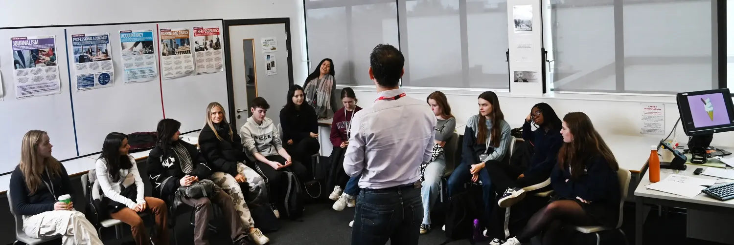 male teacher with back to camera talking to students